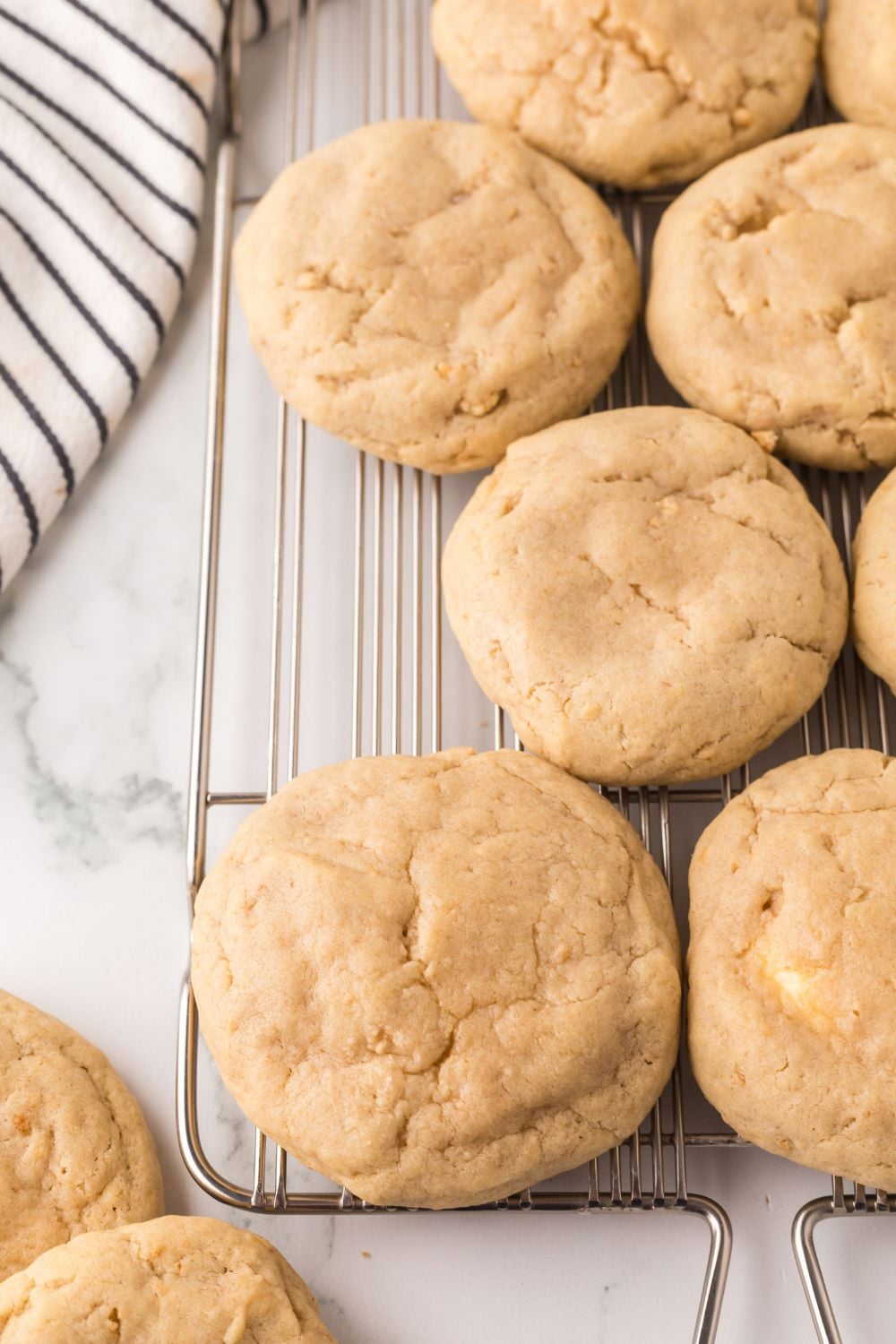 New York cheesecake cookies on a metal cooling rack with a towel to side of tray 