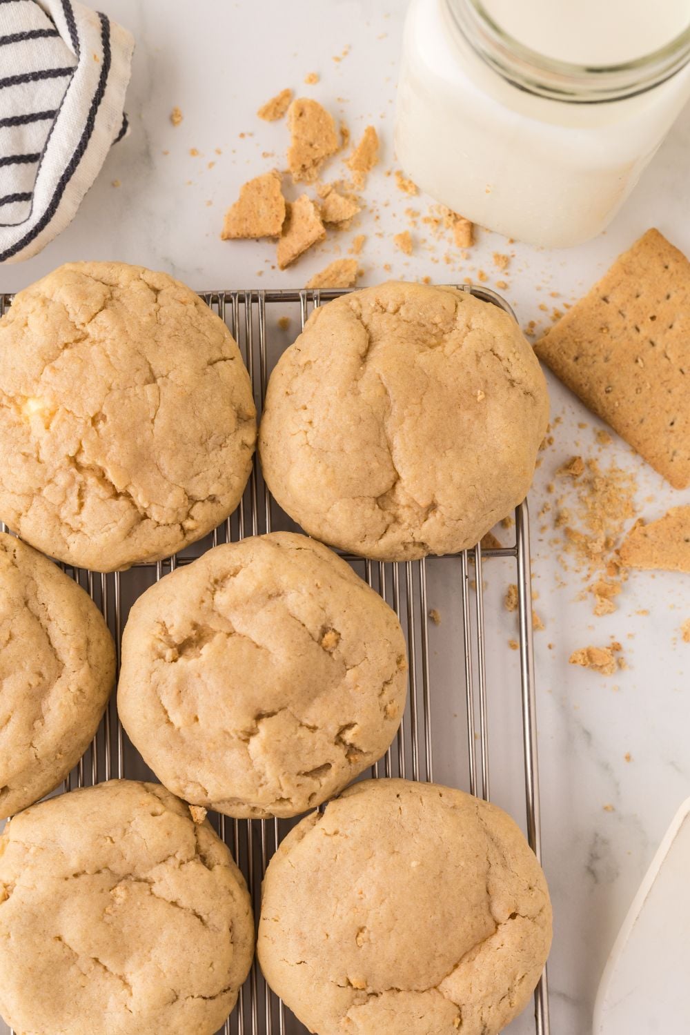 New York cheesecake cookies on a cooling rack with some graham crackers around table and crumbs 
