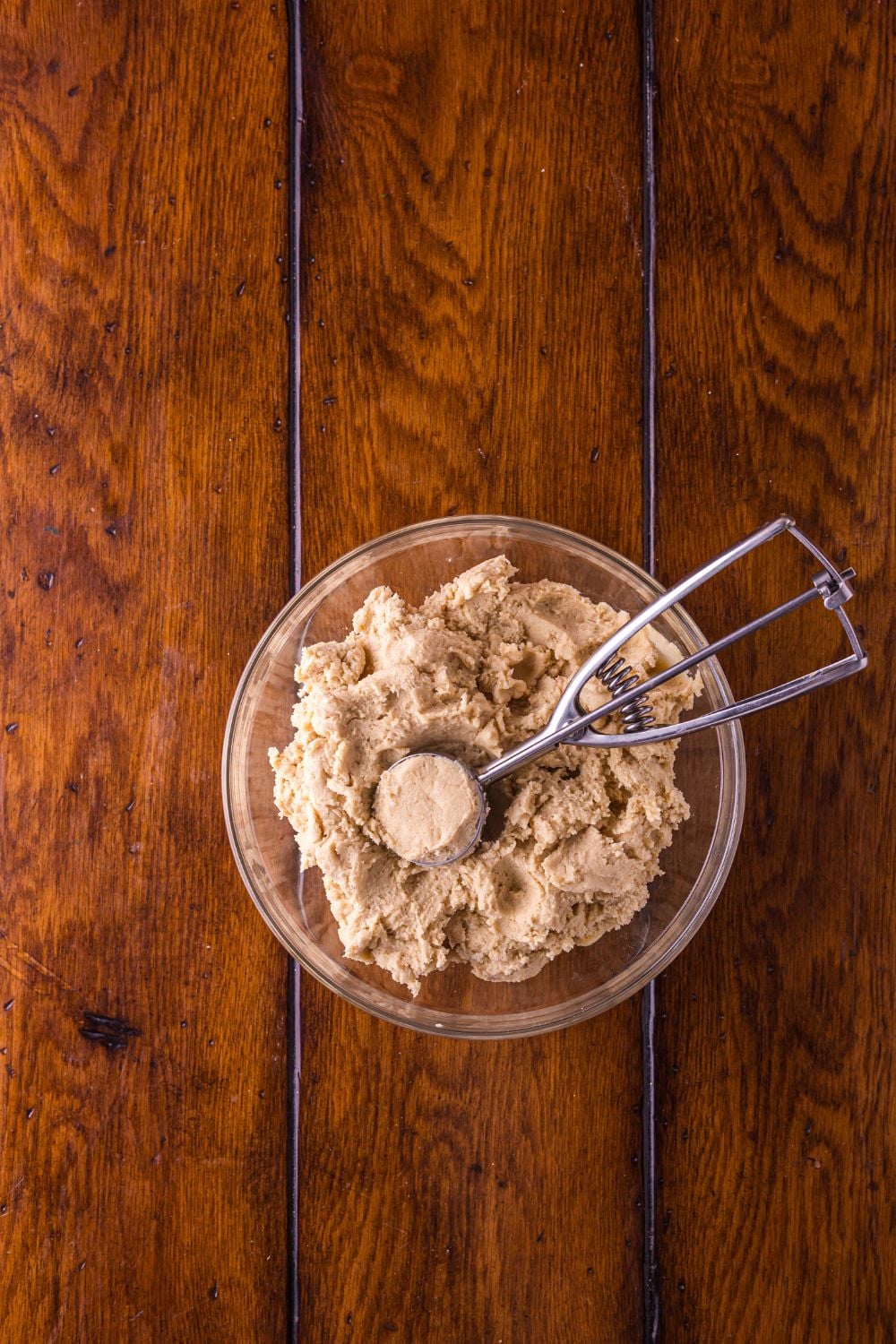 Biscoff Snickerdoodle Cookie dough in a glass bowl with a cookie scoop