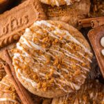 Biscoff Snickerdoodle Cookies stacked on top of one another with a Biscoff cookie to the side and white chocolate chips in a bowl