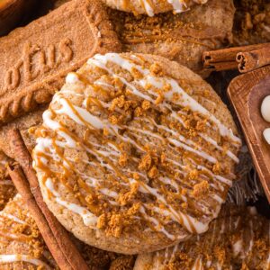 Biscoff Snickerdoodle Cookies stacked on top of one another with a Biscoff cookie to the side and white chocolate chips in a bowl