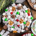Christmas Chex Mix in a bowl loaded with candies and Christmas decor around table