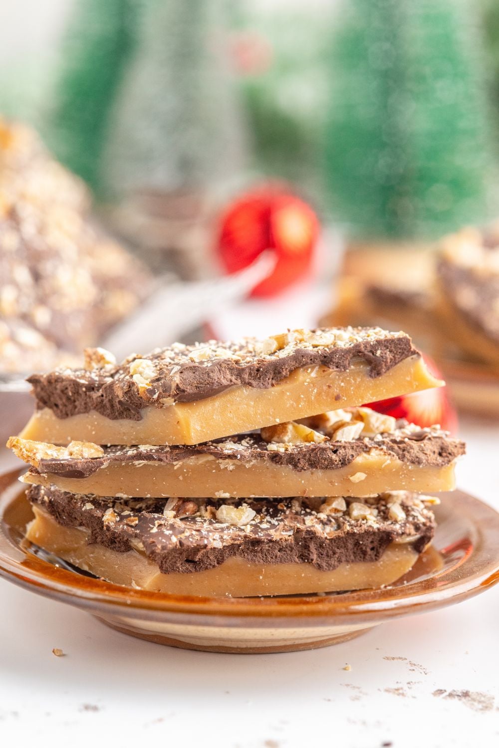 English Toffee stacked on a plate with more around the background with Christmas decor 