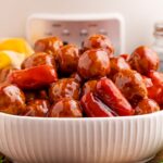 Crockpot Teriyaki BBQ Cocktail Meatballs & Lil Smokies in a white bowl on table with a crockpot behind it