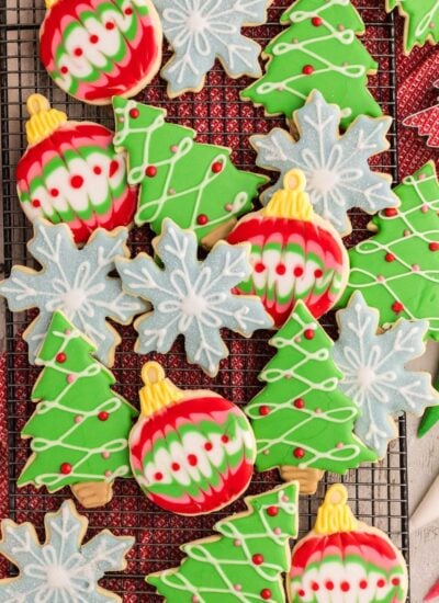 Decorated Sugar Cookies spread out on a table with rolling pin beside it and icing bags