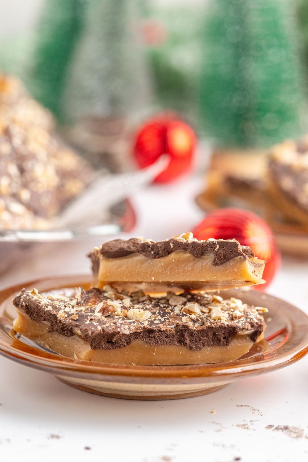 English Toffee on a plate with more behind it and some red ornaments on table 