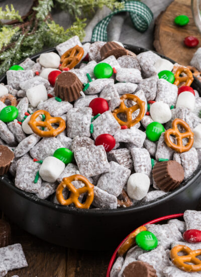 Christmas Chex Mix in a bowl loaded with candies and Christmas decor around table