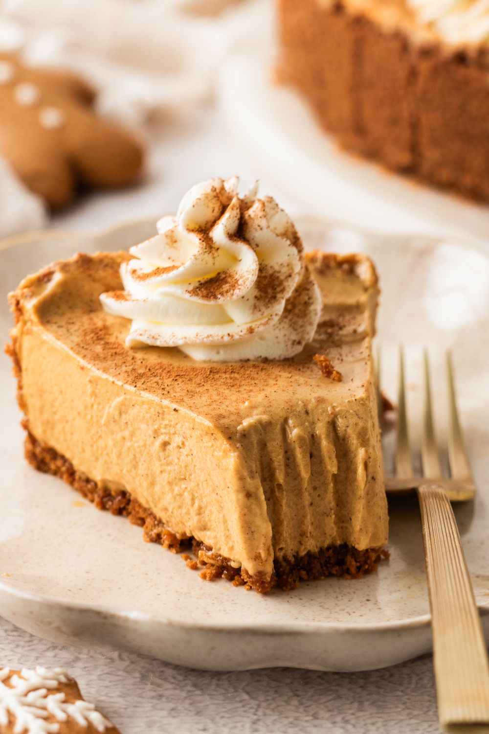 No Bake Gingerbread Cheesecake on plate with a bite taken out and a dollop of whipped cream on top 