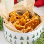 Homemade Peanut Brittle in a Christmas tin on table with Christmas decor
