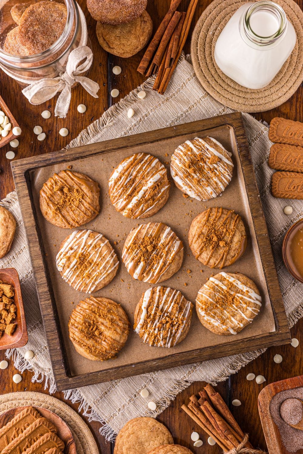 cookie sheet with Biscoff Snickerdoodle Cookies and holiday items around the pan on the table with a tall glass of milk