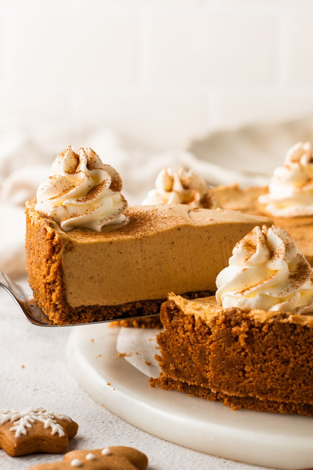 No Bake Gingerbread Cheesecake on table and a slice being lifted out of the pan 