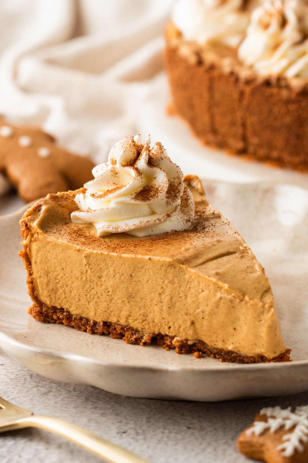 No Bake Gingerbread Cheesecake sliced on plates and placed on table with the rest of pie in the background 
