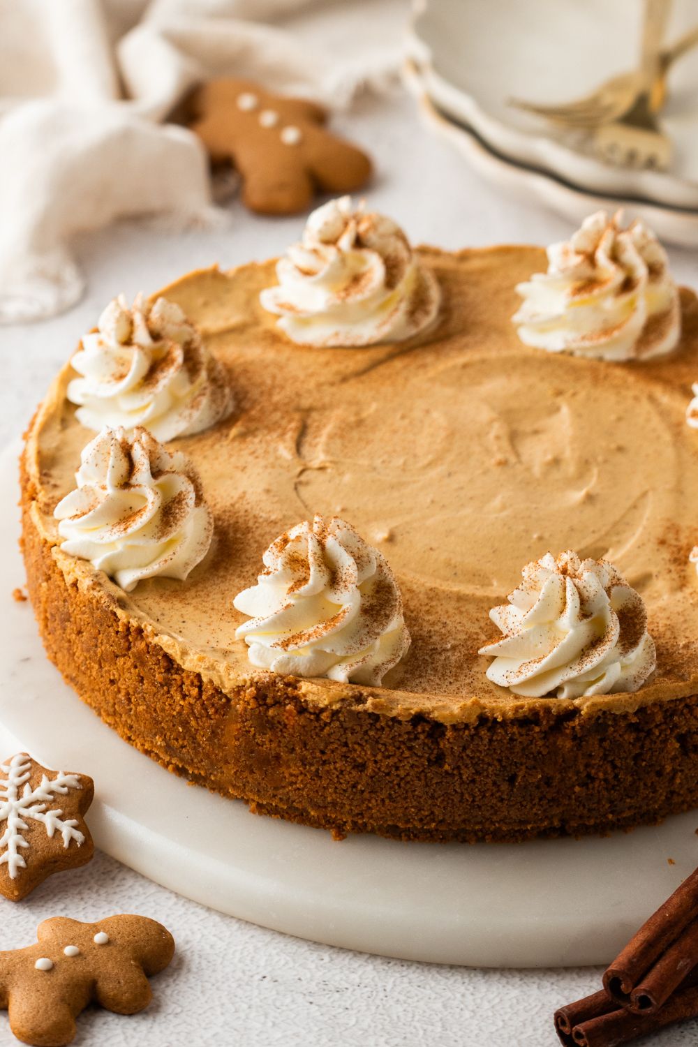 No Bake Gingerbread Cheesecake on a pie plate and gingerbread cookies around the table 