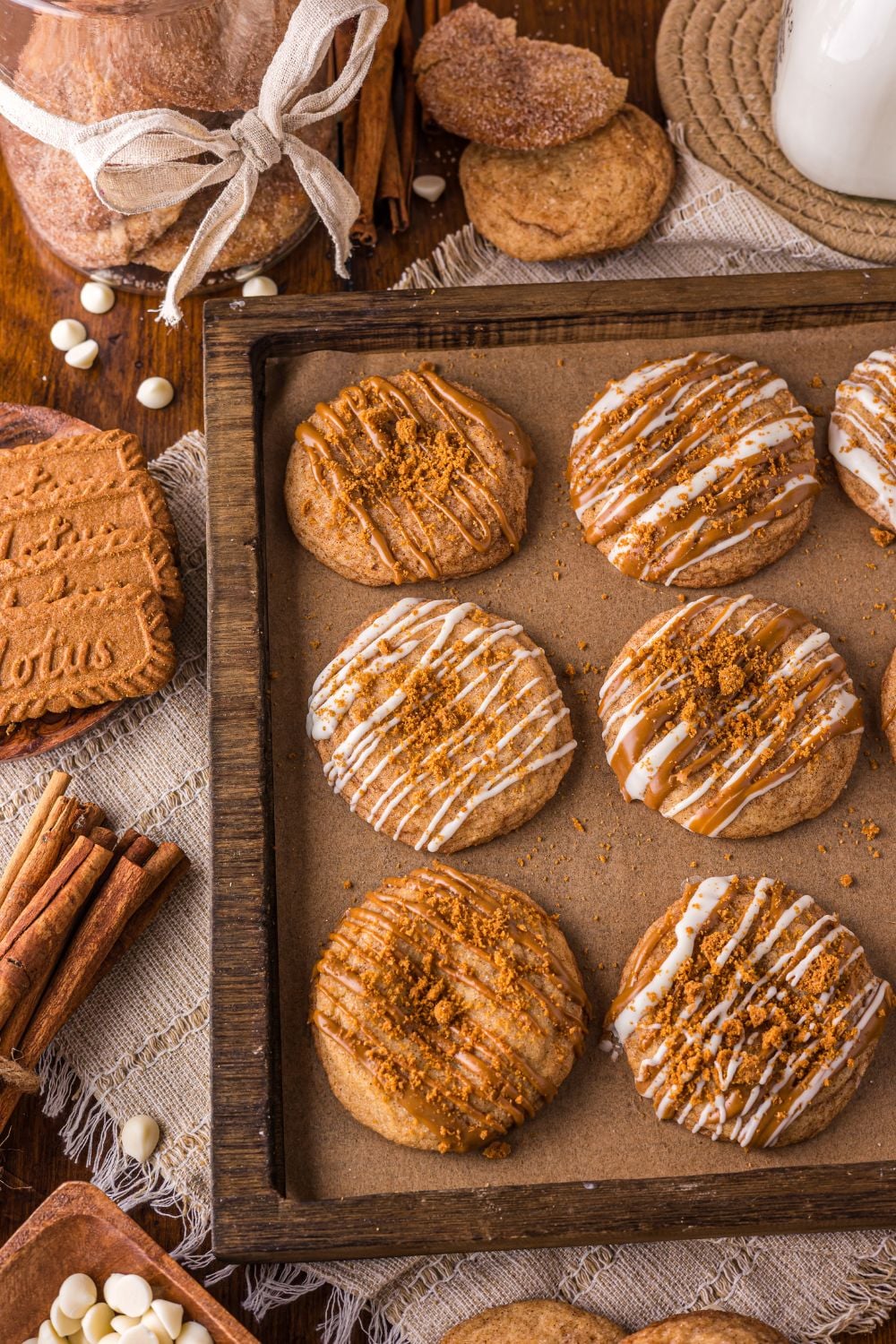Biscoff Snickerdoodle Cookies on a baking sheet with cinnamon sticks, cookies and more around the pan on table 