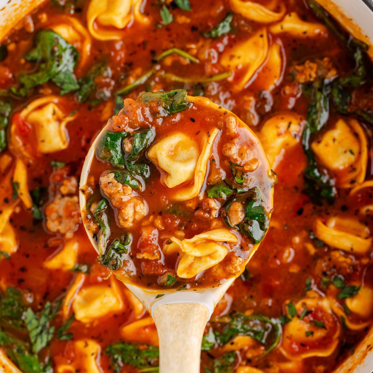 Sausage Tortellini Soup in a pot with a ladle full of some of the soup 