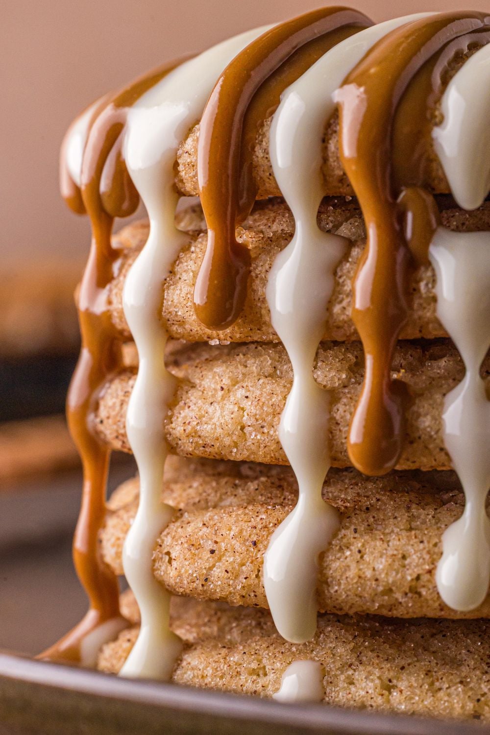 stack of Biscoff Snickerdoodle Cookies on plate with white chocolate and cookie butter dripping off the cookies 
