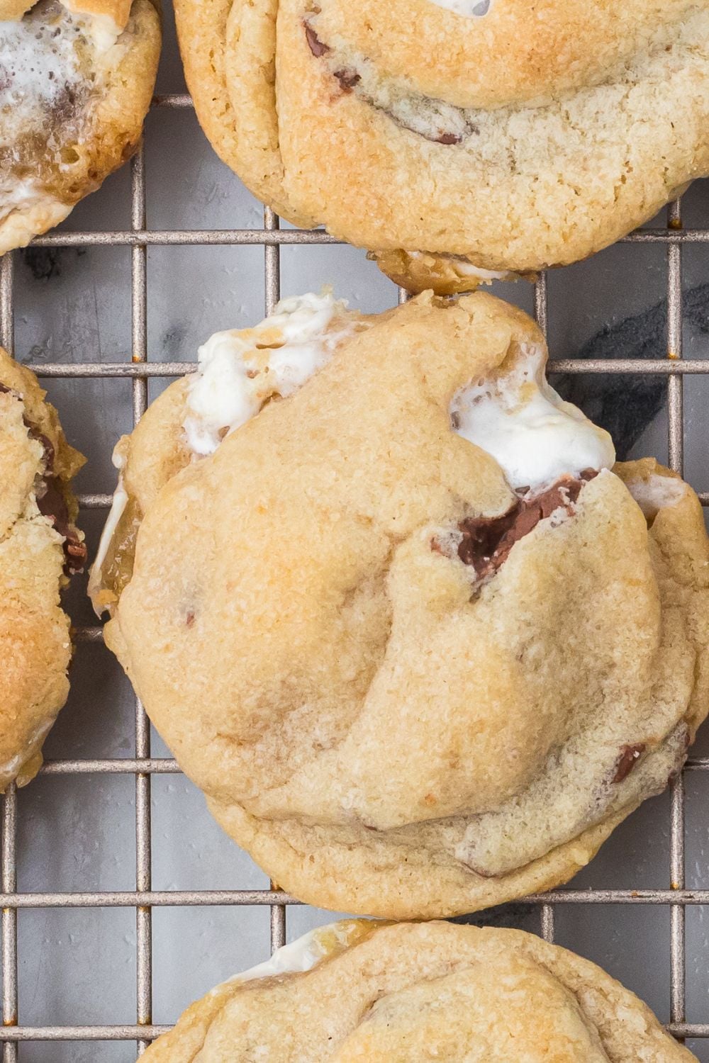 looking down on table with a metal cooling rack with rows of S'mores Cookies on it cooling 