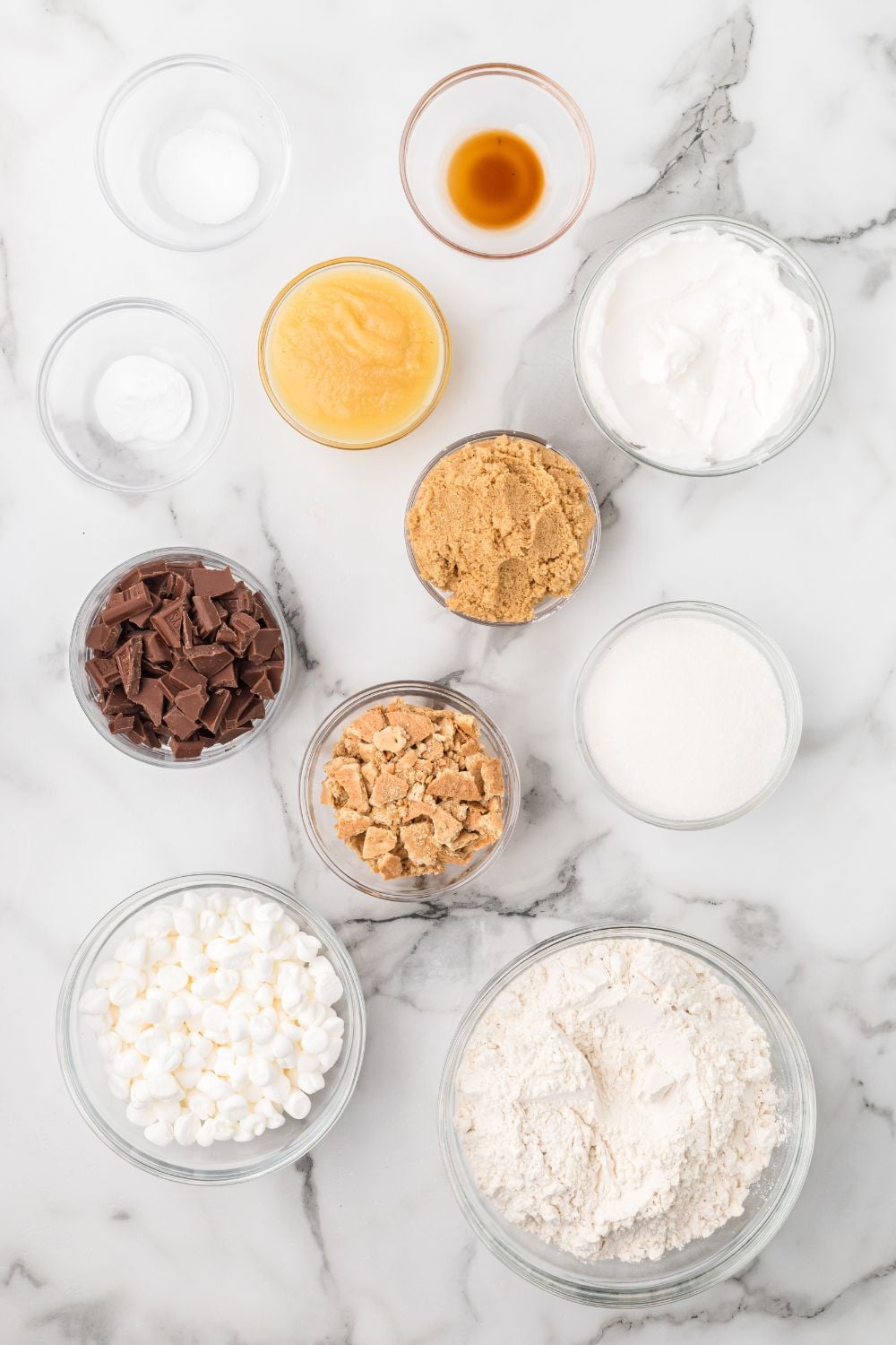 marble counter with S'mores Cookie ingredients in glass bowls 