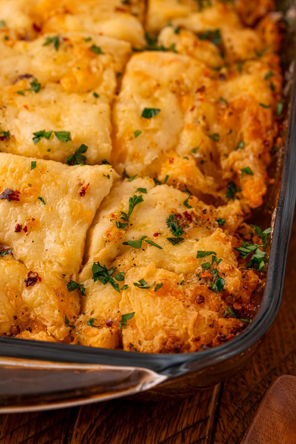 Cowboy Butter Swim Biscuits in a glass pan sitting on table topped with parsley 
