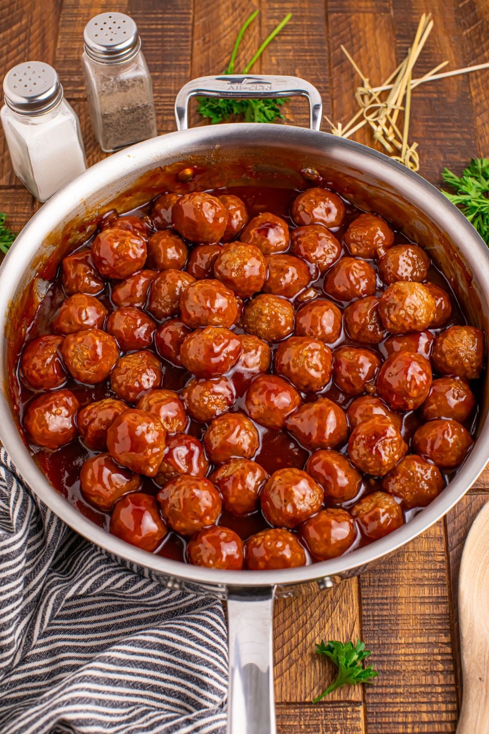 Peach BBQ Meatballs all saucy in a skillet on the table with a blue towel slightly under the pan 
