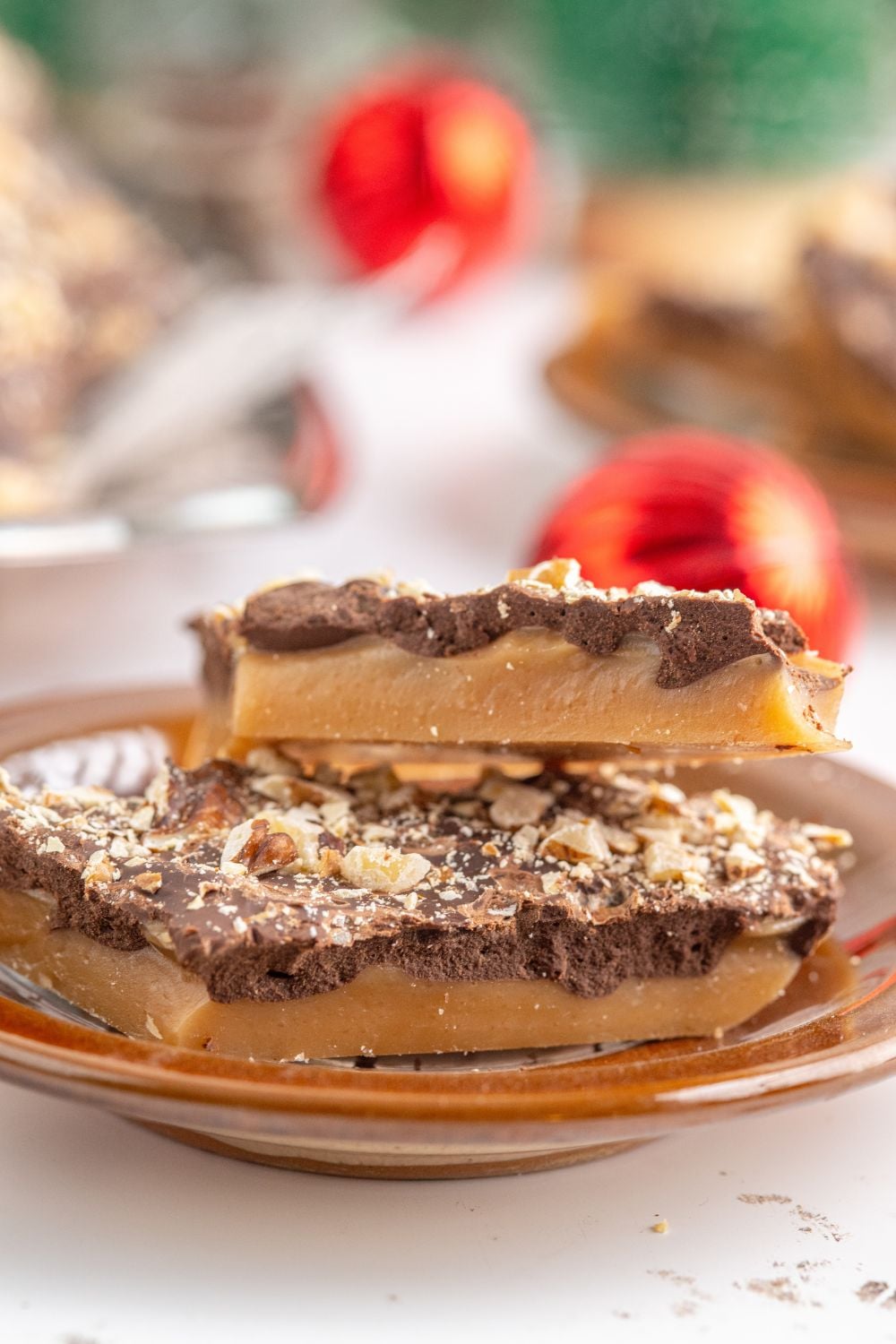 English Toffee on a plate with red ornaments behind it on table 