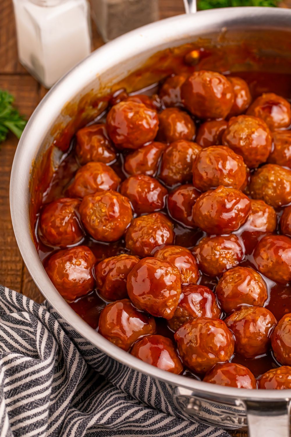 Peach BBQ Meatballs in a skillet on the table with a towel bunched beside the pan
