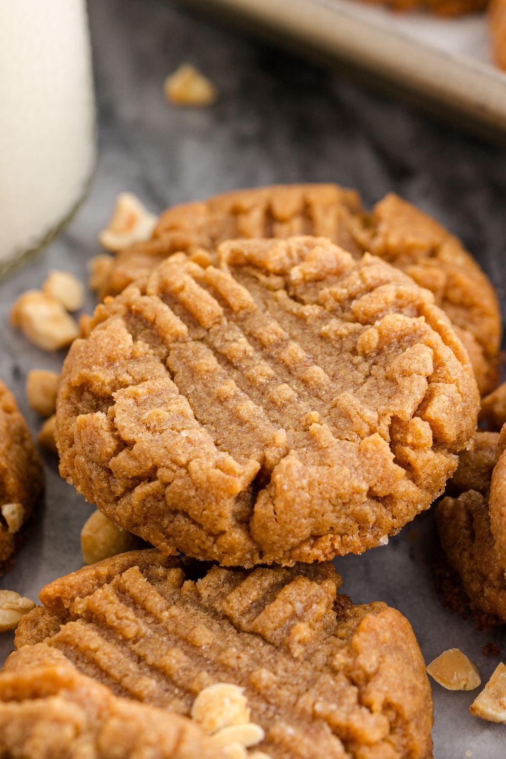 marble counter with a tall glass of milk and nuts around the cookies stacked on the table 