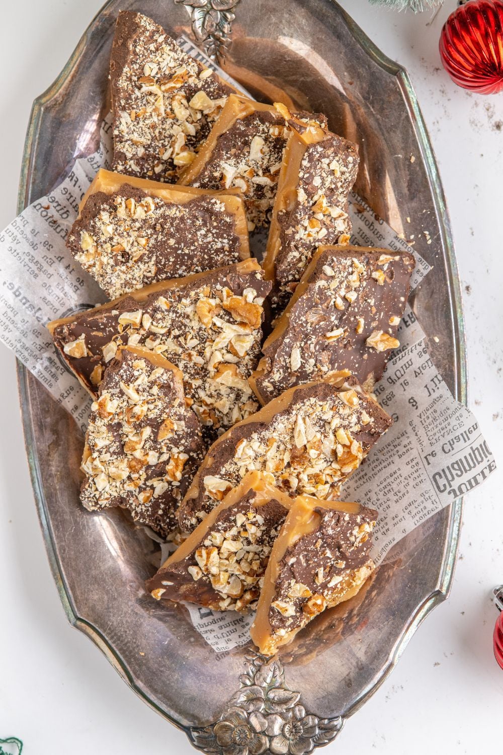 English Toffee on a silver platter on table with a Christmas ornament to the side