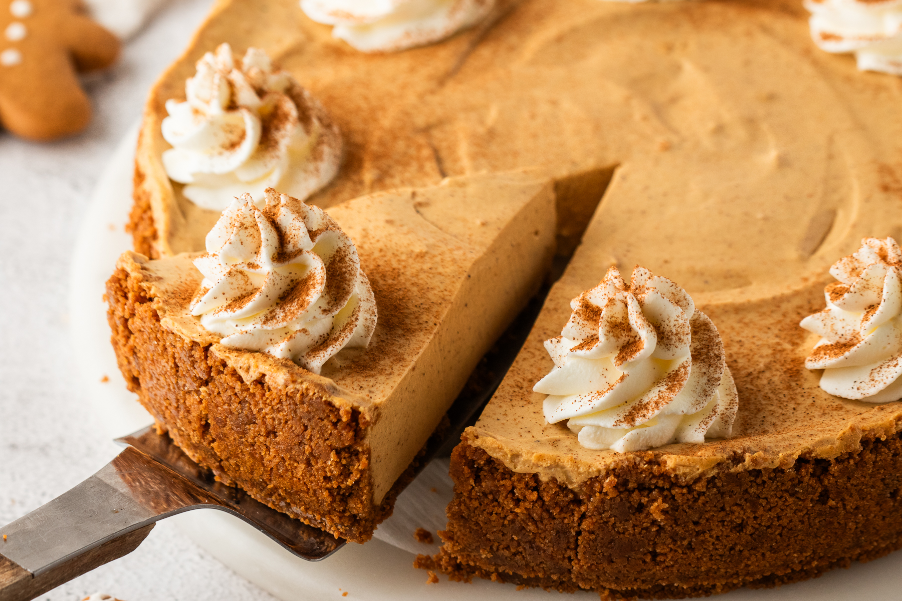 No Bake Gingerbread Cheesecake on a platter with one slice lifting out of the pie plate 