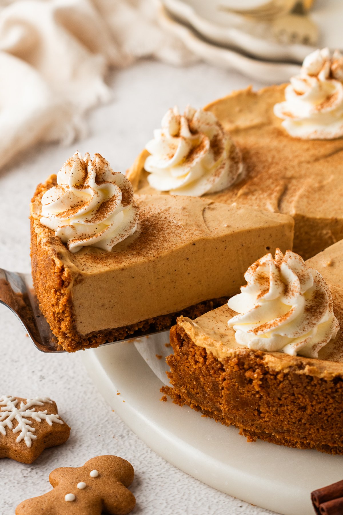No Bake Gingerbread Cheesecake on a platter with one slice lifting out of the pie plate 