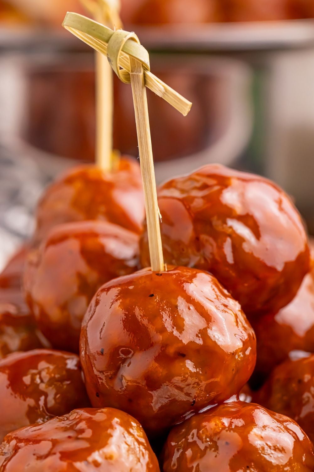 Peach BBQ Meatballs with toothpicks on it sitting in a pile on a plate 