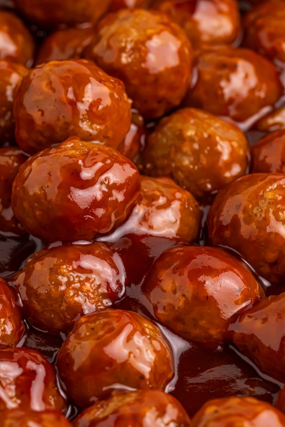 Peach BBQ Meatballs being cooked in a skillet full of sauce 
