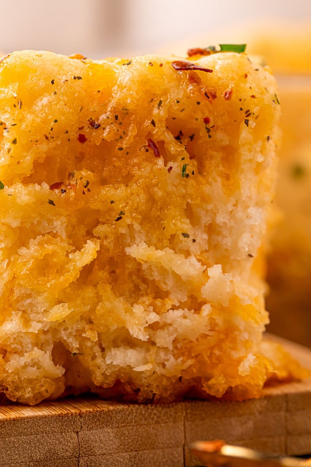 close up view of a Cowboy Butter Swim Biscuit on a wooden cutting board showing how fluffy it is and full of spices and seasoning 
