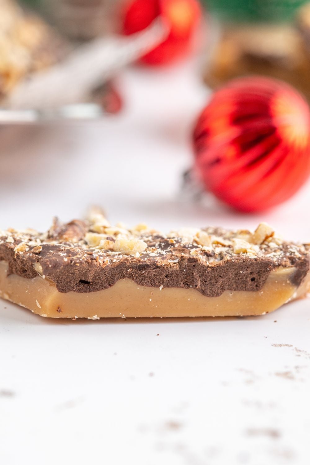 a piece of English Toffee on a white table with a Christmas ornament behind it 