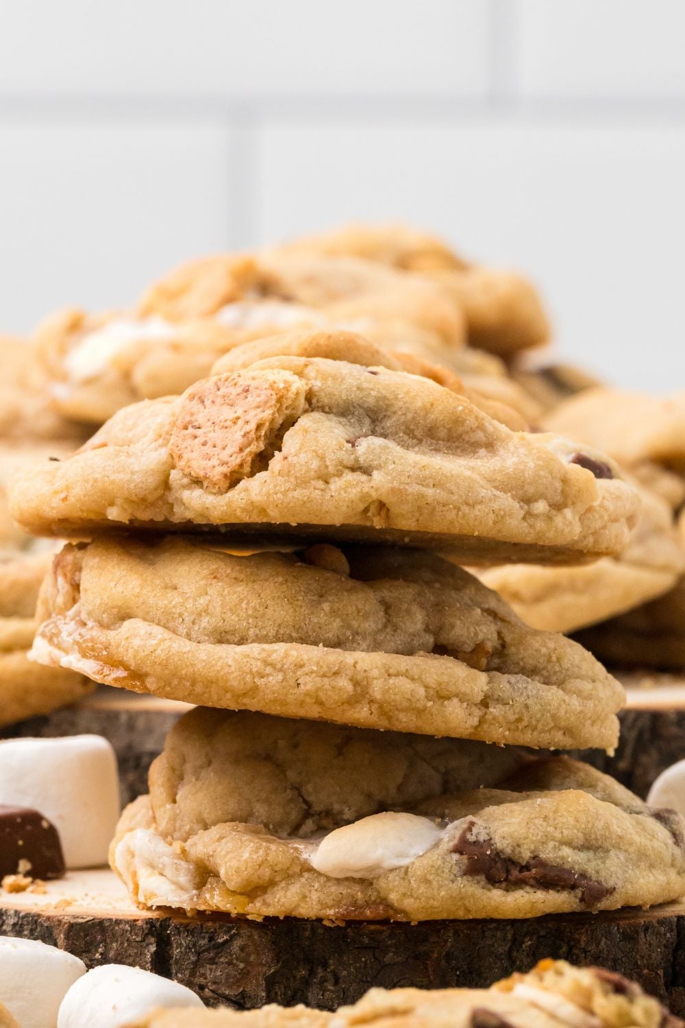 S'mores Cookies stacked on top of one another with more cookies on a plate behind it 
