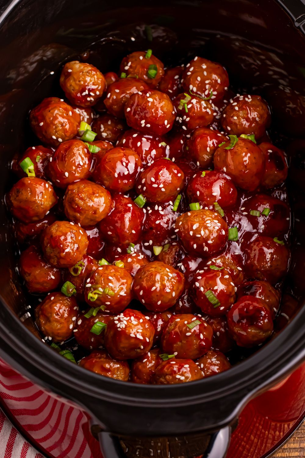 looking down on table with a black crockpot full of sweet chili meatballs 