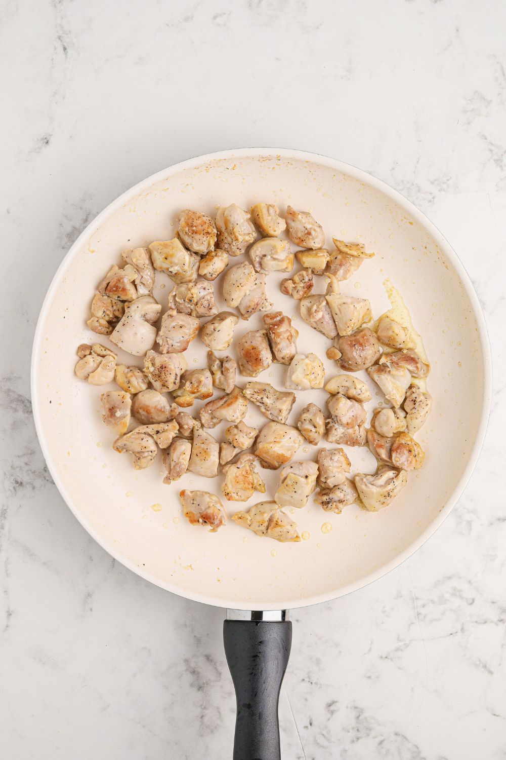 skillet of diced chicken on a marble counter