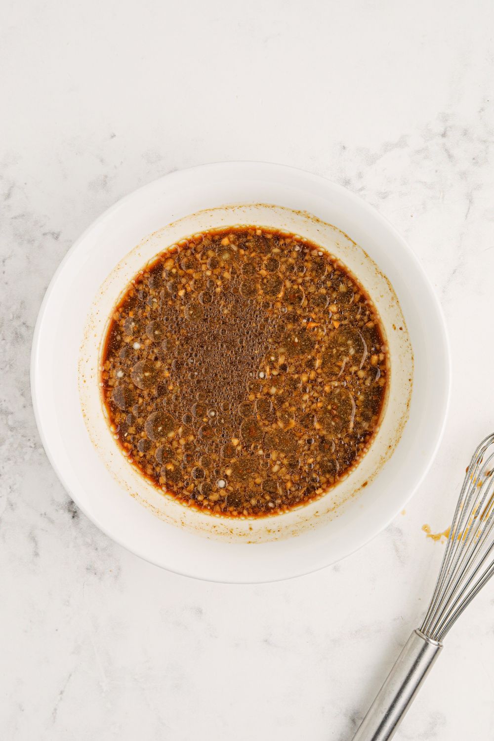 bourbon sauce in a white bowl sitting on a marble counter 
