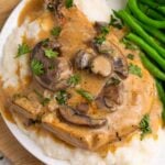 Crockpot Smothered Pork Chops with Mushroom Gravy on a plate with mashed potatoes and green beans