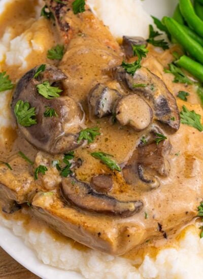 Crockpot Smothered Pork Chops with Mushroom Gravy on a plate with mashed potatoes and green beans