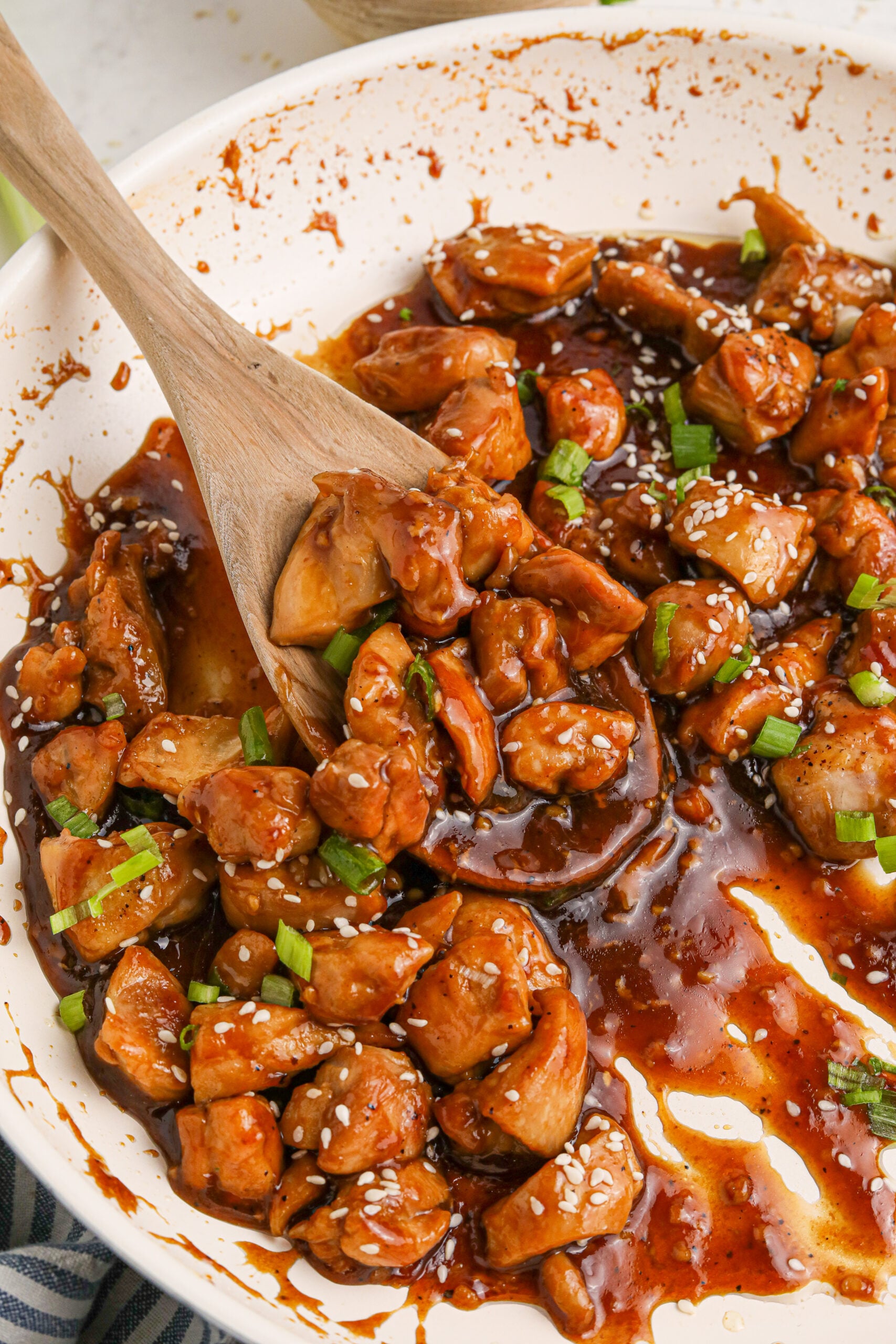 Bourbon Chicken close up in a skillet with a spoon scooping some up