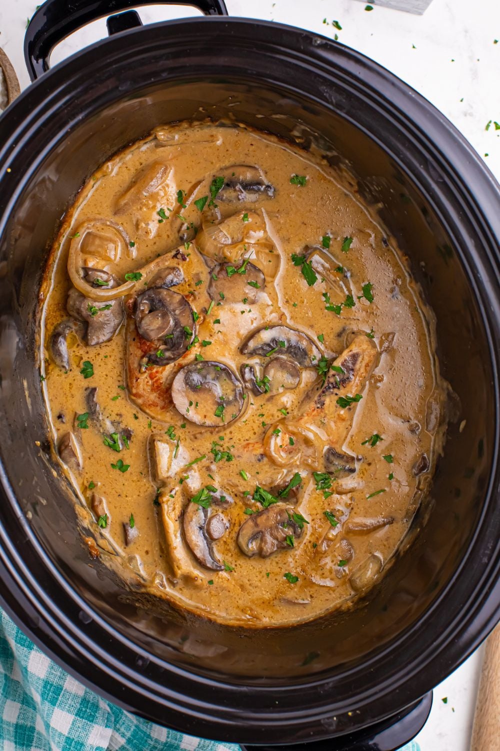 looking down on table to a crockpot with smothered pork chops with mushrooms 