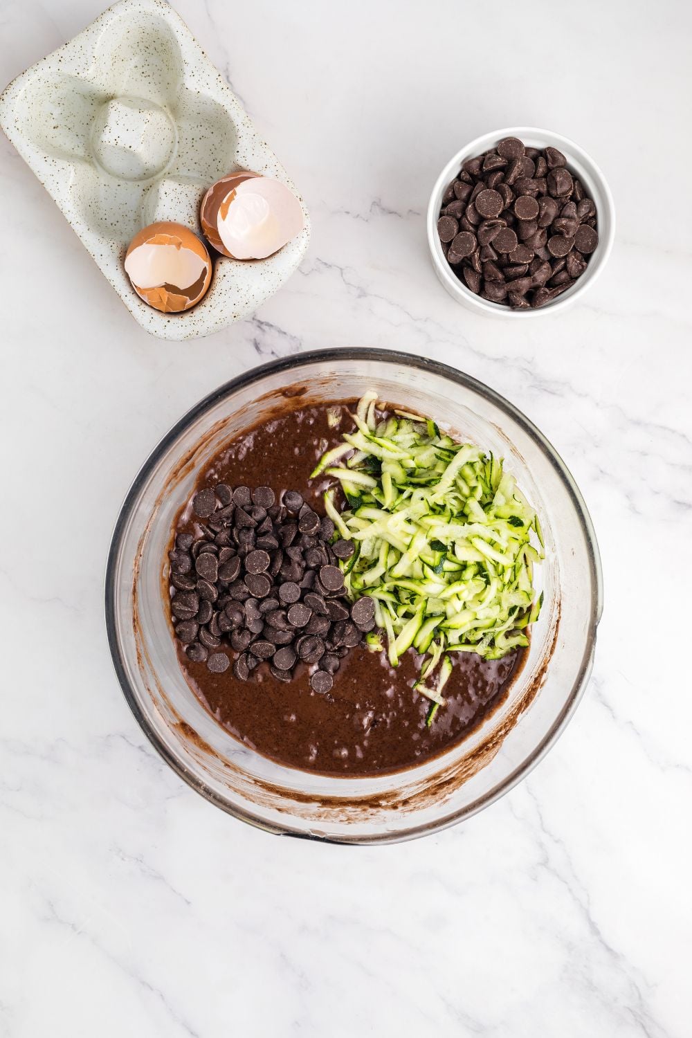 shredded zucchini and chocolate chips with Double Chocolate Zucchini Bread batter in a glass bowl