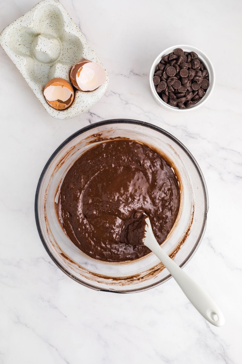 wet Double Chocolate Zucchini Bread batter in a bowl being mixed up with a bowl of chocolate chips to the side