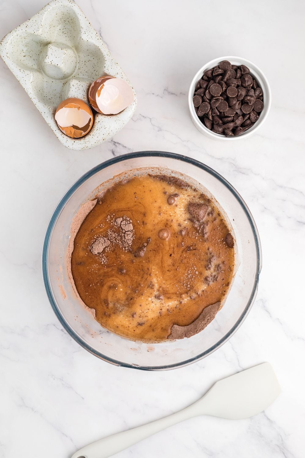 wet and dry ingredients being mixed up in a glass bowl for making Double Chocolate Zucchini Bread