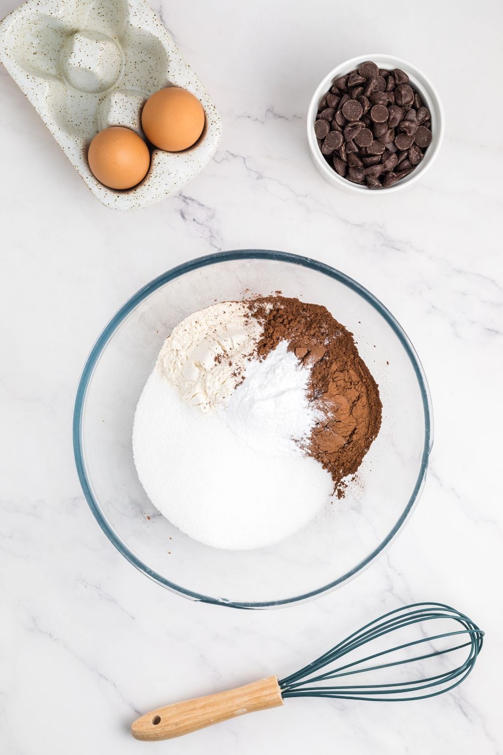 making a zucchini bread with dry ingredients in a glass bowl on the marble counter