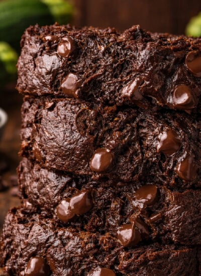 Double Chocolate Zucchini Bread sliced and placed on a white plate with zucchini in the background