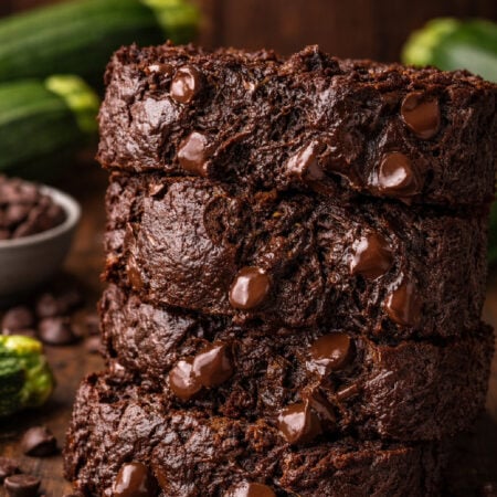 Double Chocolate Zucchini Bread sliced and placed on a white plate with zucchini in the background