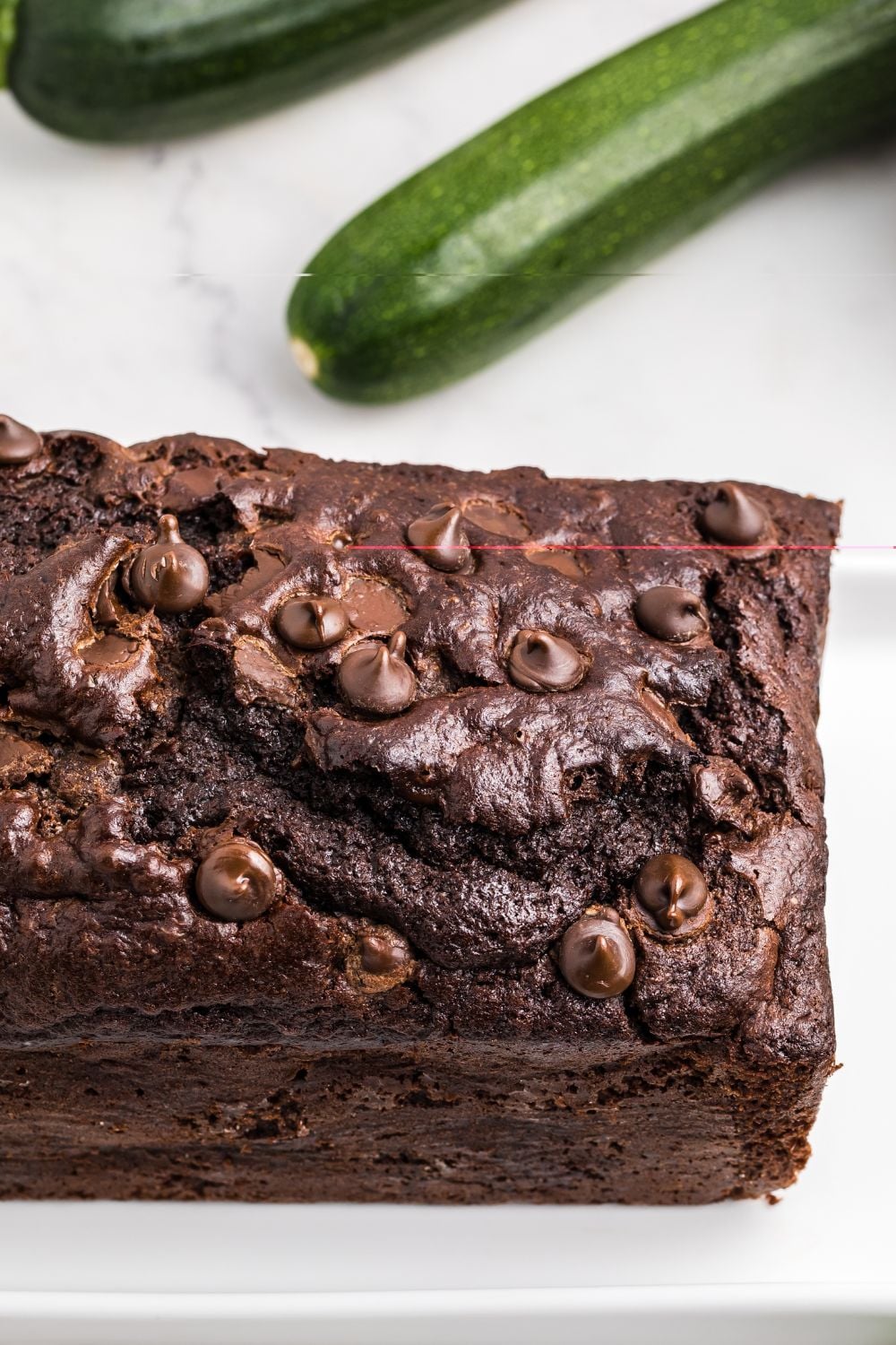 Double Chocolate Zucchini Bread on a tray with zucchini behind the table 