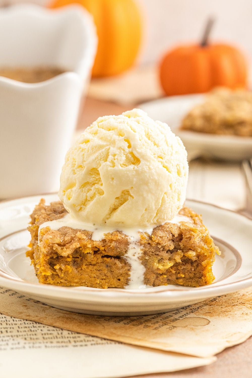 Homemade Pumpkin Crisp sliced and placed on the plate with a scoop of vanilla ice cream on top melting down 